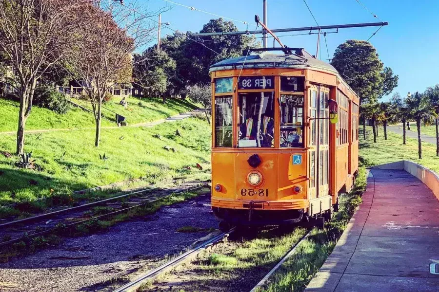 The historic, orange F Line Streetcar rolls down a track in San Francisco's 菲德尔·卡斯特罗 neighborhood.