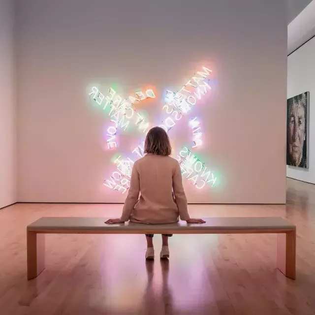 A woman, seated on a bench, looks at a piece of contemporary light art at SF MOMA in 贝博体彩app.