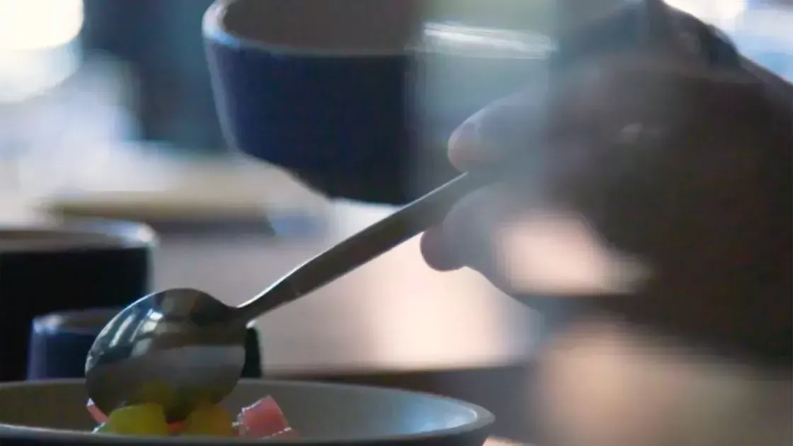 A ladle pours sauce over A plate of food.